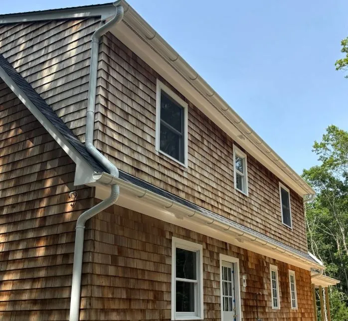 Side of a cedar-shake home with gutters and downspouts