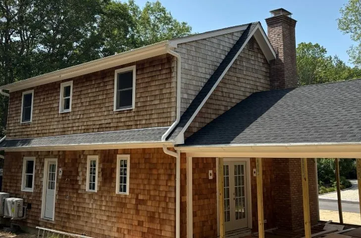Two-story cedar-shake home with white gutters along the roofline